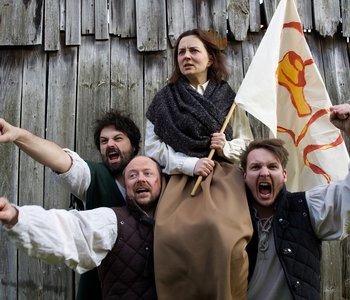 Das Bild zeigt 5 Personen, die eine Fahne hochhalten und kämpferisch schauen.