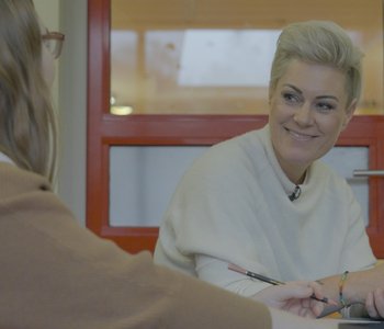 Fernsehärztin Doc Caro spricht mit Patientin, die man nur von hinten sieht