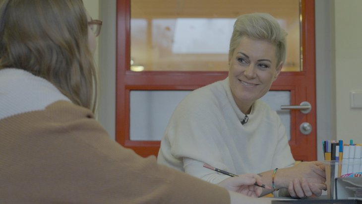 Fernsehärztin Doc Caro spricht mit Patientin, die man nur von hinten sieht